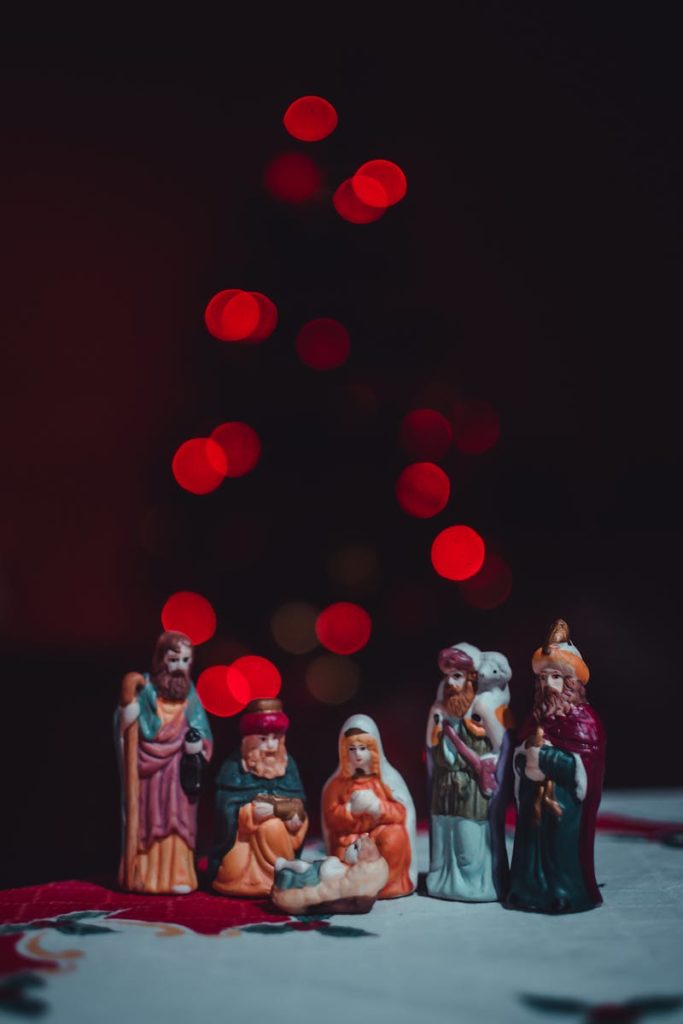 A beautifully lit nativity scene featuring miniature figurines and festive bokeh lights in the background.